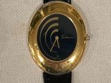 une montre noire et dorée posée sur un tissu blanc