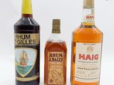 trois bouteilles d'alcool sont alignées sur une surface blanche