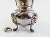 a silver vase that is sitting on a white surface