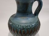 un vase bleu posé sur une surface blanche