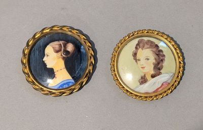 deux portraits miniatures de femmes dans des cadres dorés, posés sur une table