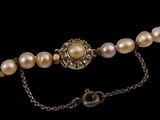 a close up of a necklace with pearls on a chain