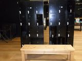 several black lockers and a bench in a room with wooden floors
