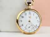 a close up of a gold pocket watch on a marble table