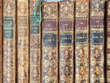 several old books are lined up on a shelf in a library