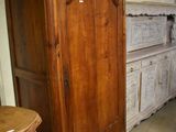 a wooden cabinet in the corner of a room next to a table