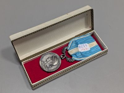 une médaille d'argent dans une boîte sur laquelle figure une médaille