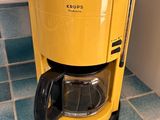 a yellow coffee maker sitting on a blue tiled floor