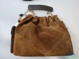 brown sued handbag with black leather handle on white surface