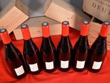 six bottles of red wine are lined up on a table