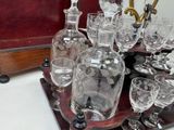 bottles and glasses on a wooden tray with a tray of wine glasses