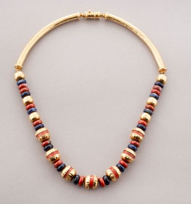 un collier en or orné de perles multicolores sur fond blanc