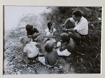 photographie en noir et blanc représentant un groupe de personnes assises au bord d'une rivière