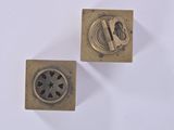 two small metal objects on a white surface with a white background