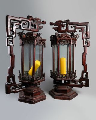 deux lanternes en bois contenant chacune une bougie jaune