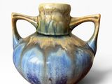 a blue and brown vase with handles on a white background