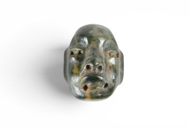 un gros plan sur une sculpture représentant un visage sur une surface blanche