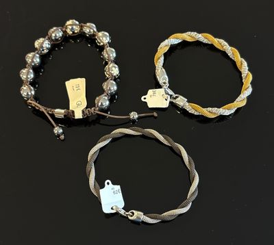 trois bracelets ornés de perles argentées et d'une étiquette, sur un fond noir