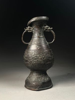 a large metal vase with a bird on top of it
