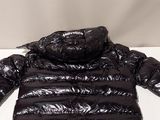 the black puffer jacket is laying on a white surface