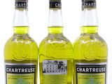 trois bouteilles de Chartreuse sont alignées sur une surface blanche