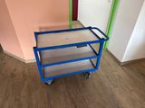 un chariot bleu posé sur un parquet, près d'un mur rose