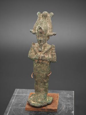 une ancienne statue en bronze représentant un homme coiffé d'un chapeau