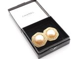 a pair of earrings in a box on a white surface