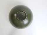 a green vase sitting on a white surface with a tag on it