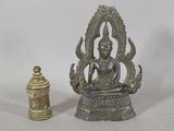 une statue de Bouddha assis en position du lotus, à côté d'une petite cloche