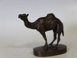 statue représentant un chameau, posée sur un socle en bois, sur une surface blanche