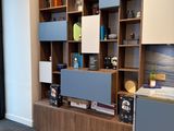 a room with a table, bookshelf, and a refrigerator in it