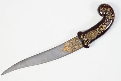 a knife with a decorative handle on a white surface