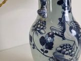 a blue and white vase on a table with a lamp on it
