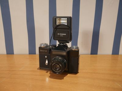un appareil photo posé sur une table, surmonté d'un flash