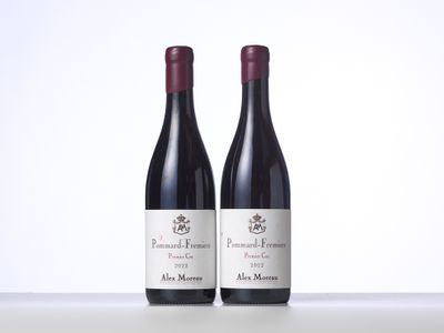 two bottles of red wine sitting on top of a white table