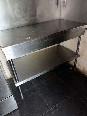 a stainless steel table with a shelf underneath it in a kitchen
