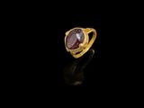 une bague en or sertie d'une pierre rose sur fond noir