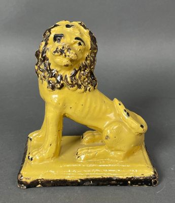 une figurine de lion jaune posée sur un socle noir
