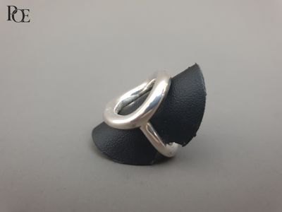 un gros plan d'une bague en argent posée sur un morceau de cuir noir