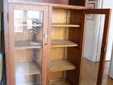 a wooden cabinet with a glass door in a room