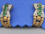 une paire de boucles d'oreilles en émeraude et diamant posées sur un tissu bleu