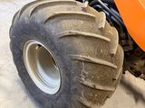 a large orange tractor with a big tire in a garage