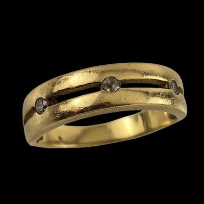 un gros plan d'une bague en or sertie de diamants sur fond noir