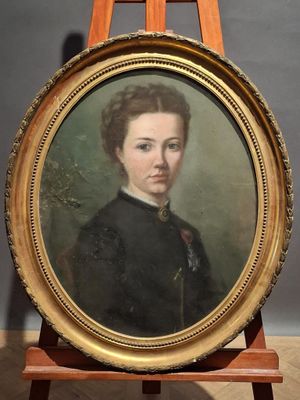 portrait of a woman in a black dress in a gold frame on a wooden easel