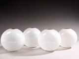 quatre vases blancs sont alignés sur une surface blanche