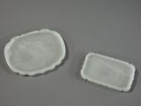 two white dishes on a table with a gray background