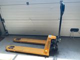 un chariot élévateur jaune garé devant la porte d'un garage
