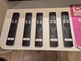 cinq télécommandes posées sur une étagère devant un téléviseur