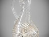 a clear glass pitcher with a curved handle on a gray background